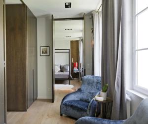 a living room with a blue chair and a bedroom at Les Jardins du Panthéon in Paris