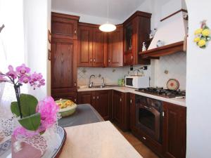 a kitchen with wooden cabinets and a vase of flowers on the counter at Villa Patrizia by Interhome in Forte dei Marmi +22 photos