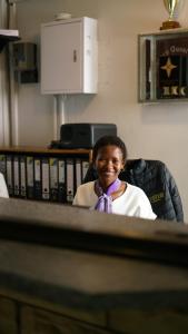 a woman sitting in a chair wearing a purple tie at Scenery Guesthouse Stadium in Maseru