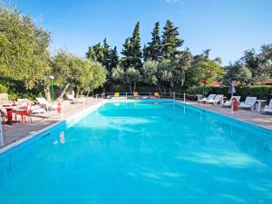 a large blue swimming pool with chairs and a table at Studio Borgoverde-12 by Interhome in Imperia