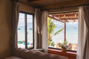 a bedroom with a view of the beach from a window at Ruby's Home- Doc Let's House in Ngân Hà