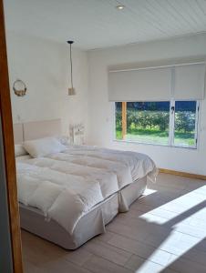 a white bedroom with a large bed and a window at Le Clos La Perdiz in Pigüé +10 photos