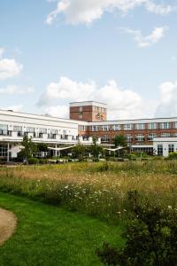 a large building with a field in front of it at Van der Valk Hotel Apeldoorn in Apeldoorn