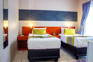 a hotel room with two beds with yellow pillows at Scenery Guesthouse Stadium in Maseru