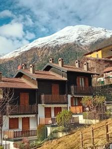 a building with a snow covered mountain in the background at Villetta Eden Schilpario in Schilpario