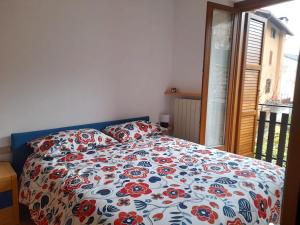 a bed with a flowered comforter in a bedroom at Villetta Eden Schilpario in Schilpario