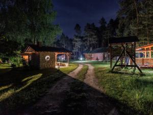 a dirt road with a house and a shed at night at Domki Nad Tanwią in Susiec