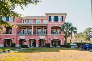 a pink building with a yard in front of it at Coastal Quarters Condo in Bluffton