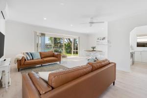 a living room with two brown leather couches at The Water House - Lakeside Serenity & Modern Comfort in Encounter Bay