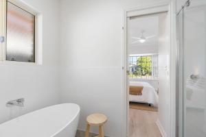 a white bathroom with a tub and a bedroom at The Water House - Lakeside Serenity & Modern Comfort in Encounter Bay +35 photos