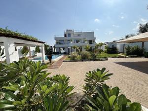 a large white house with a swimming pool in a yard at Villa Samara - 10p - 5bdr - Diani Beach - Piscine in Magutu