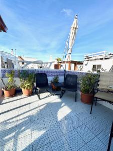 a balcony with chairs and an umbrella and potted plants at Zenit Olhao baixa one bedroom house sea side view in Olhão