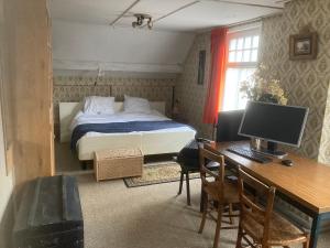 a bedroom with a bed and a desk with a computer at Het werkhuis, terug in de tijd in Uden