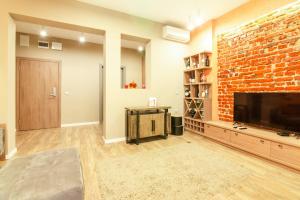 a living room with a brick wall and a flat screen tv at 1 BR Wine Journey in Sofia