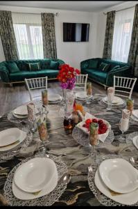 a dining room table with plates and flowers on it at Casa Aida in Peşteana