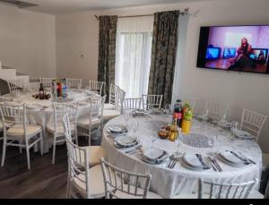 a dining room with white tables and chairs and a television at Casa Aida in Peşteana