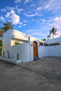 a white house with a door and palm trees at Villa Casa de Coco at Lovina in Lovina