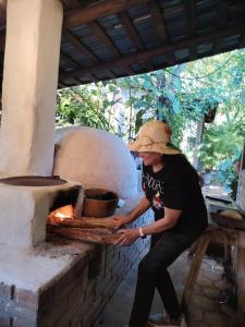 a woman in a hat is putting something into an oven at Hotel de Campo Villa de Ada in Gracias