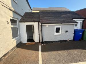eine graue Garage mit einem Tor neben einem Gebäude in der Unterkunft Gemini 2 in Great Wyrley