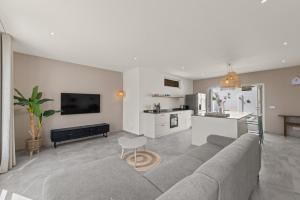 a living room with a gray couch and a kitchen at Cura Kaat - Ruime 4 slaapkamer villa met zwembad op gated resort in Jan Thiel