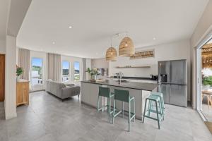 a kitchen with a counter and stools in it at Cura Kaat - Ruime 4 slaapkamer villa met zwembad op gated resort in Jan Thiel