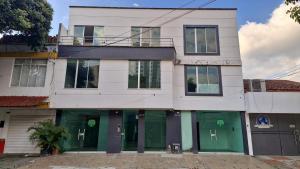 a white building with green doors on a street at Loft 204 - H54 WAIWA HOST in Bucaramanga