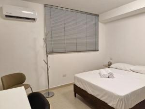 a white bedroom with a bed and a window at Loft 204 - H54 WAIWA HOST in Bucaramanga