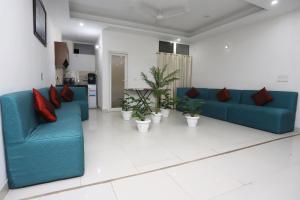 a living room with blue couches and potted plants at Capital O Levanti Near Aravali Biodiversity Park in Gurgaon