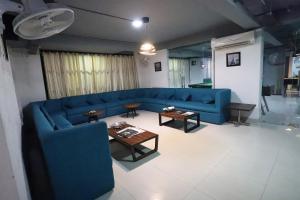 a living room with a blue couch and tables at Capital O Levanti Near Aravali Biodiversity Park in Gurgaon +32 photos