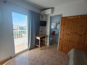 a bedroom with a bed and a desk and a balcony at Hostal Bélgica in Palmanova