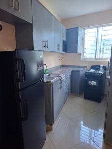 a kitchen with blue cabinets and a black refrigerator at Doña Minda Home in Naiboa