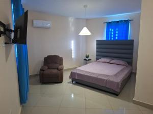 a bedroom with a bed and a chair at Doña Minda Home in Naiboa