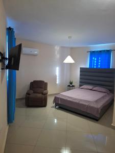 a bedroom with a bed and a chair and a television at Doña Minda Home in Naiboa +8 photos