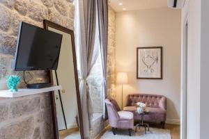 a living room with a tv and a couch and a chair at Dubrovnik Deluxe Rooms in Dubrovnik +33 photos