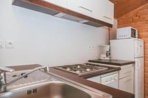 a kitchen with a sink and a stove and a refrigerator at ZEcamping 3 étoiles dog friendly avec piscine couverte et chauffée in Monclar-de-Quercy