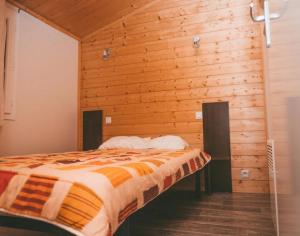 a bed in a room with a wooden wall at ZEcamping 3 étoiles dog friendly avec piscine couverte et chauffée in Monclar-de-Quercy