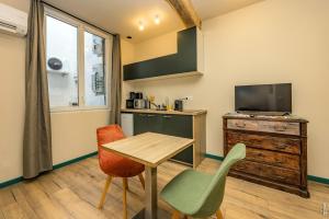 a living room with a table and chairs and a tv at Le Figuier - Studio de Charme in Lavaur +9 photos