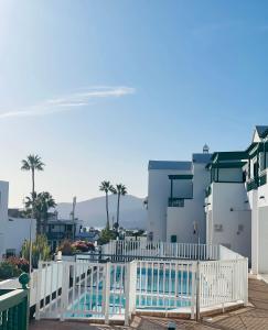 a white fence with a pool in front of a building at -MONTORIAN View LANZAROTE- in Puerto del Carmen