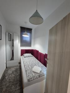 a bedroom with a bed with a red head board at Studio Apartman 47B in Valjevo