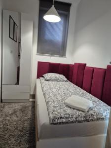 a bed with a red headboard in a room at Studio Apartman 47B in Valjevo