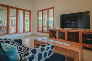 a living room with a tv and a table and chairs at Villa Le Tito in Lovina