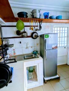 a small kitchen with a refrigerator and a sink at Appartement Meublé 3 Chambres in Douala