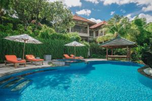 a swimming pool with chairs and umbrellas next to a house at Villa Le Tito in Lovina