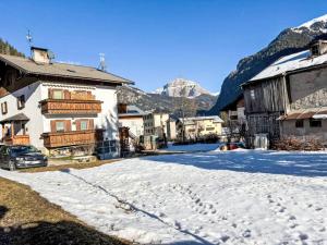 a snowy street in a village with mountains in the background at Apartment Cristina by Interhome in Campestrin