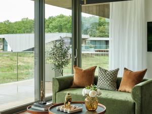 ein Wohnzimmer mit einem grünen Sofa und großen Fenstern in der Unterkunft Escapade Silverstone in Towcester