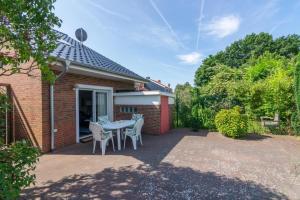 a patio with a table and chairs in front of a house at Ferienhaus-Mackeriege in Norden