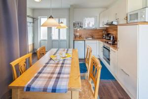 a kitchen with a table and chairs and a kitchen with white cabinets at Ferienhaus-Mackeriege in Norden