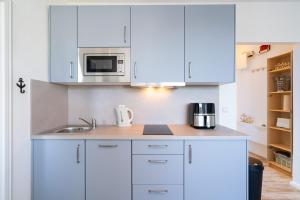 a white kitchen with a sink and a microwave at Solymar Whg 64 in Grömitz