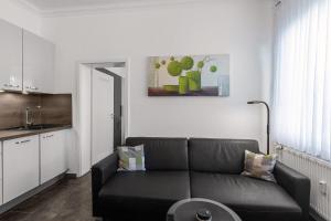 a living room with a black couch and a kitchen at Solymar Whg 11 in Grömitz
