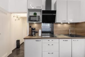 a kitchen with white cabinets and a sink and a microwave at Solymar Whg 11 in Grömitz +10 photos